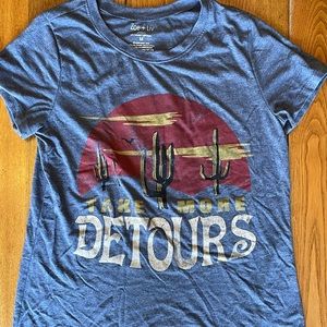 A girls tee shirt. Blueish grey and says “take more detours” with a desert scene